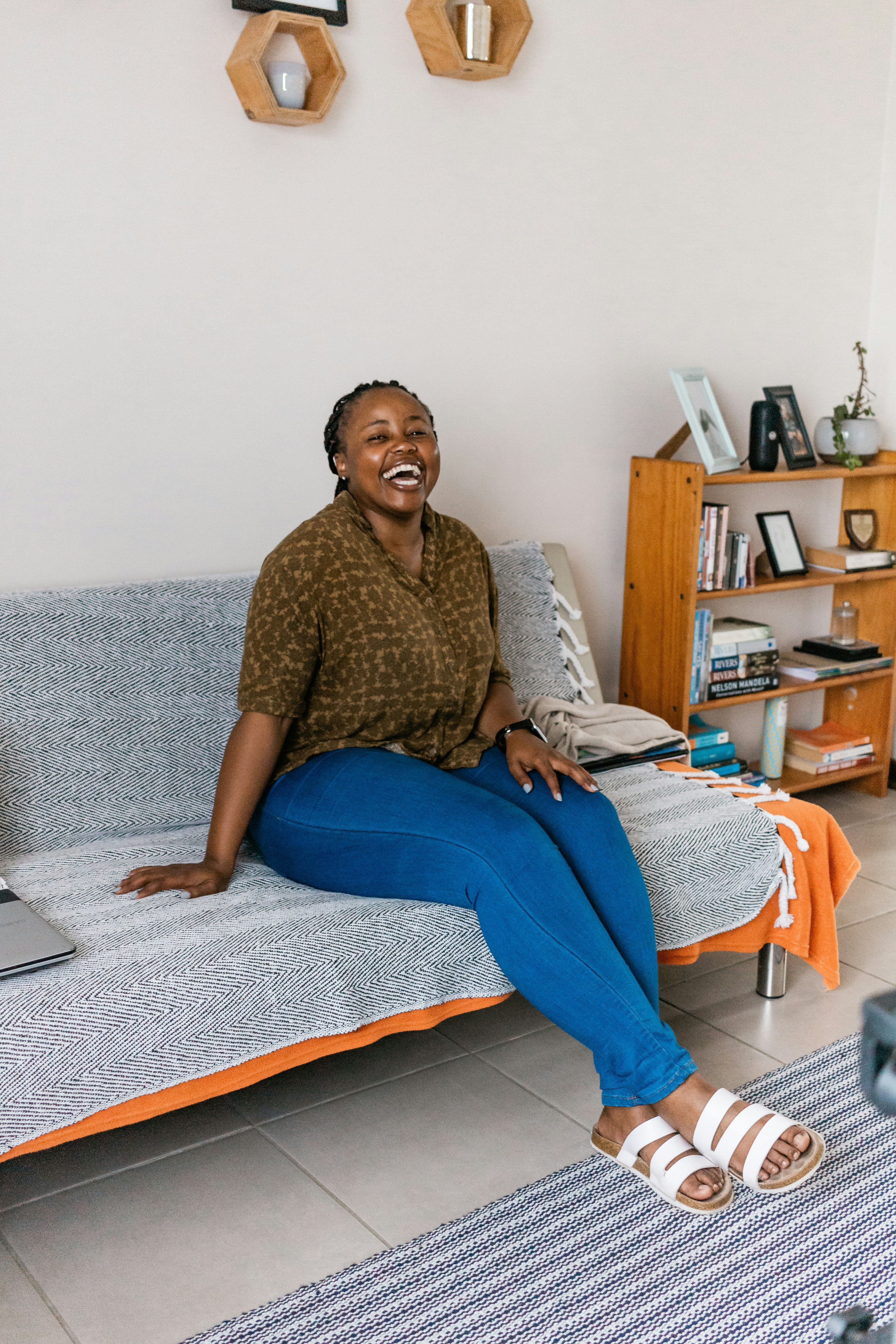 woman in brown long sleeve shirt and blue denim jeans sitting on bed